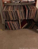 Photo showing multiple records stored on a wooden rack, arranged tightly with worn edges visible.