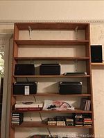 Full view of wooden shelving unit with storage boxes, CDs and 8-track tapes on shelves.