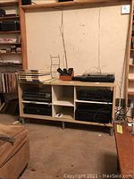 Wide view of the wooden cabinet showing overall structure, worn surface, missing doors, and exposed compartments along with some nearby items.