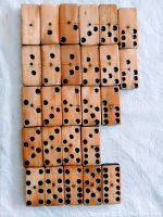 Top-down view of 26 antique bone and ebony domino pieces arranged closely together, showing the front faces with black pips and natural ivory bone coloration.
