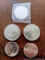 Obverse side of five Canadian coins showing Queen Elizabeth II portraits. One coin sealed in original mint packaging. Other coins show wear and discoloration.