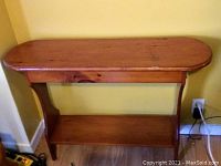 Full view of the handmade solid wood sofa table or plant stand showing top surface, legs, and lower shelf against the wall.
