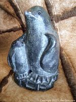 Front left angle view of the resin sculpture showing the penguin standing next to the chick on a detailed base.