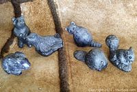 Six different resin animal carvings arranged on a brown fabric background: a standing bear, a seal, a rabbit, a squirrel, a beaver, and a bird.