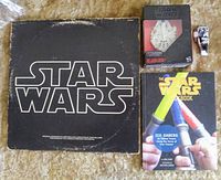 Photo showing the original Star Wars soundtrack LP, the Star Wars Cookbook, the Millennium Falcon Titanium Edition die cast vehicle in box, and an Imperial Forces die cast figure all together.