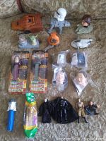 Full lot of Star Wars collectibles including Troop Carrier, PEZ dispensers, bobble head vehicles, Rubik head puzzles, action figures, and Yoda levitator on a couch with fabric background