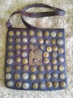 Front view of vintage handmade leather pouch adorned with mixed metal coin studs in grid pattern and central embossed leather flap.