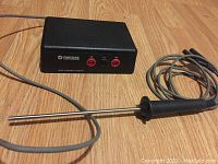 Photo of black Chrysler Corporation Low Current Shunt box with 3 ports (2A, (-), 10A) and a metal temperature probe with black handle connected by gray cable.