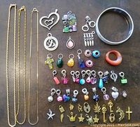 Full view of the assortment including chains, pendants, charms, bangle bracelet, and glass ring.