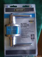 Photo of new Defiant Olympic Collection bed and bath door lock in original packaging showing product features and branding