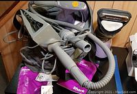Photo showing Shark SC630W steam cleaner with attached cords and hoses in grey and purple color.