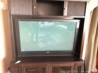 Front view of a 50-inch Sanyo television in a wooden cabinet showing the screen and bezel.