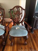 Front view of a shield-back cherry wood captain chair with carved claw feet and light sage microfiber seat.