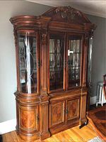 Front view of two-piece wooden hutch with glass doors and ornate carvings
