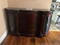 Front view of the Samuel Lawrence marble top credenza showing the four curved central drawers and two curved glass side doors, standing on a hardwood floor against a wall.