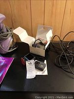 GoPro camera with accessories laid out on black surface including a small open white box.