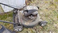 Photo of Bolens 21-inch push lawn mower showing left side, engine housing, and wheels with weathered condition and dirt.