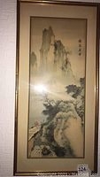 Full view of larger Asian-inspired ink brush landscape painting framed in golden bamboo style frame.
