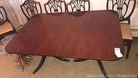 Full view of rectangular dark brown wood dining table with six matching chairs arranged around it