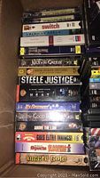 Stack of VHS tapes and DVDs showing titles like Jesus of Nazareth, Steel Justice, American Dream, and others.