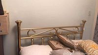 View of the full size brass bed frame headboard with pillows placed on mattress.