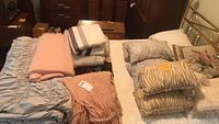 Photo showing a selection of pillows and folded blankets laid out on bed frame