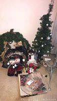 Full view of holiday decorations including the decorated artificial Christmas tree, snowman figure, wreath, candle, and glass platter with assorted decorations.