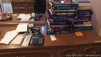 Books, calculator, envelopes, and other office items on a wooden desk