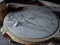 Top view showing oval marble surface with gray veining and minor chips.