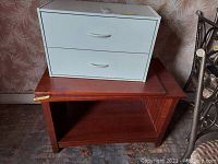 Wooden TV stand with white 2-drawer storage unit on top, showing the surface and size comparison