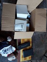 Opened cardboard box containing a folded wooden chess/checker board with storage boxes and a stuffed monkey toy wearing a soccer jersey beside the box