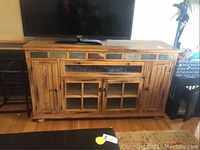 Front view of wooden cabinet with TV on top showcasing the design and condition including slate paneling and wood finish.