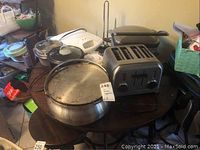 Overview photo showing all items on a table including toaster, griddle, skillets, crockpot, steamer, pot, and waffle maker.