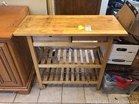 Front angled view of the pine wood food prep cart with visible drawers and slatted shelves, showing wear on the top surface.