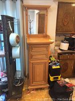 Side angle showing light brown stained bathroom vanity cabinet with mirror, drawers, and cupboard.