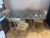 Front angle showing entire table with glass top and chairs surrounding it.