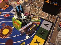 Photo of assorted kids games including Paw Patrol wooden puzzles, Apple to Apples Junior game, Star Wars walkie talkies, and other toys on colorful alphabet and animal-themed rug.