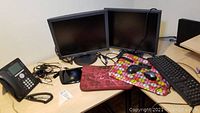 Two monitors, two laptop cases, office phone, keyboard, two mice and cables on a desk.