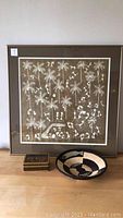 Framed Inca style picture, decorative woven bowl, and wooden box on table