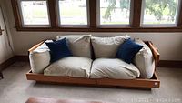 Front view of pine wood sofa frame with beige cushions and two blue accent pillows.