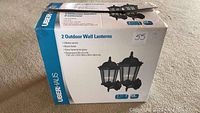 Box showing the brand Uberhaus and product image with two outdoor wall lanterns.