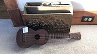 Ukulele leaning against carved magazine holder in overall view