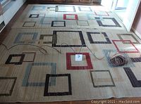 Full view of one matching throw rug showing colors, square pattern, the off white/cream background and overall size