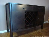 Angled front view showing overall piece with drawers, cabinets, and wine rack