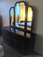 Wide dresser with three-panel arched mirror reflecting mattress
