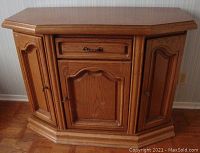 Front view of the wooden storage hutch showing drawer and cabinet doors with decorative molding and hardware.