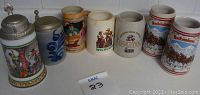 Photo showing all seven German beer steins in a row, two marked Budweiser, various designs including floral, traditional costumes, and brewery logos.