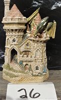 Front and angled side view of the stone castle figurine with pink roofs and a green dragon.
