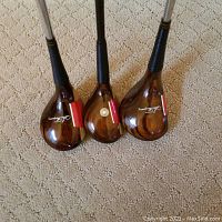 Three wooden-headed golf clubs showing small wood heads with Stan Thompson branding and red stickers.