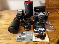 Overview of camera body, lenses, flash, cleaning kit, manuals and cases on table